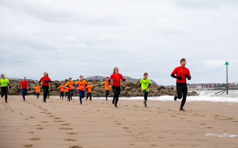 pobl yn rhedeg ar y traeth