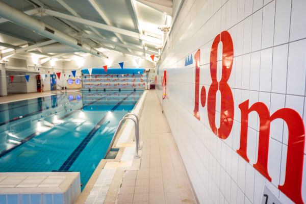 Depth indicator signage on wall of swimming pool.
